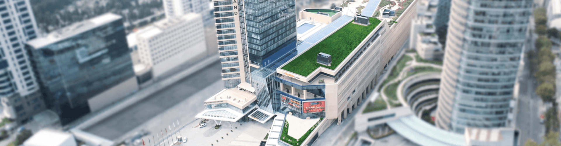 Luftaufnahme des Wyndham Grand-Gebäudes mit grünem Dach und umliegender Stadtlandschaft.