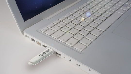 White laptop with a Rational-branded USB stick inserted into a USB port.