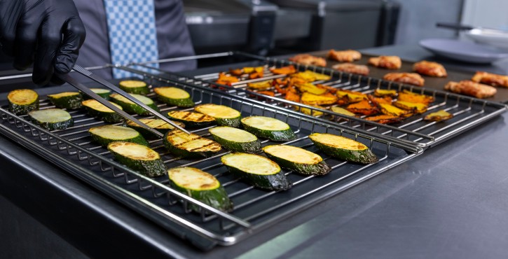 Chef disposant des légumes grillés sur un plateau pour le RATIONAL iCombi Pro four mixte.