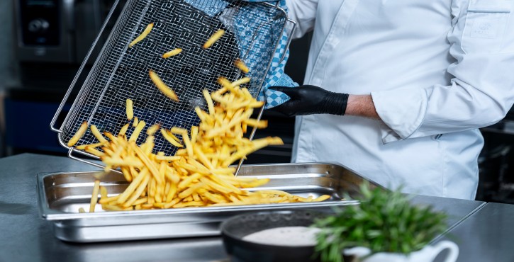 Chef versant des frites du panier dans le bac après cuisson dans le RATIONAL iCombi Pro four mixte.