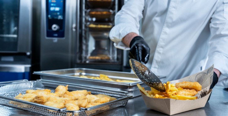 Chef servant du fish and chips près du RATIONAL iCombi Pro four mixte.
