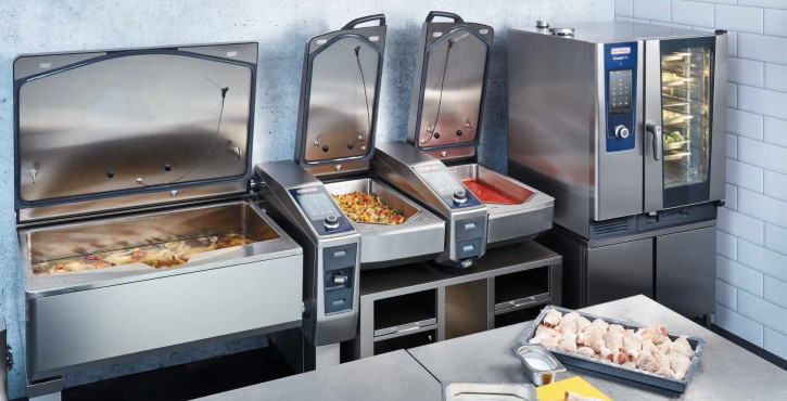 A kitchen setup showcasing the iCombi Pro and iVario Pro units. Ingredients like onions and chicken wings are prepared on the counter.