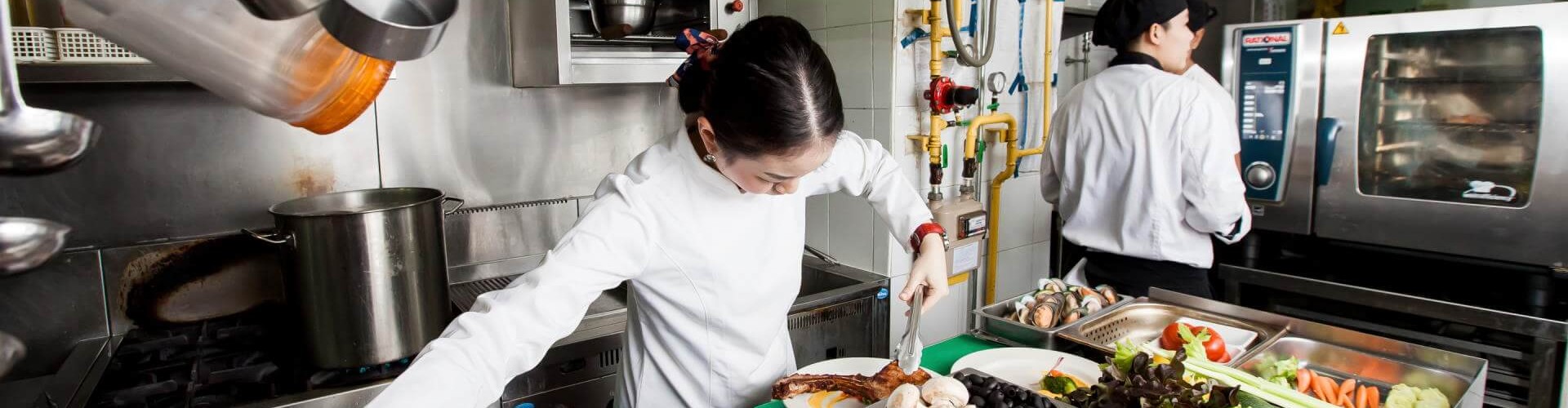 厨师在繁忙厨房中于RATIONAL iCombi Pro 混合蒸锅旁准备食材。