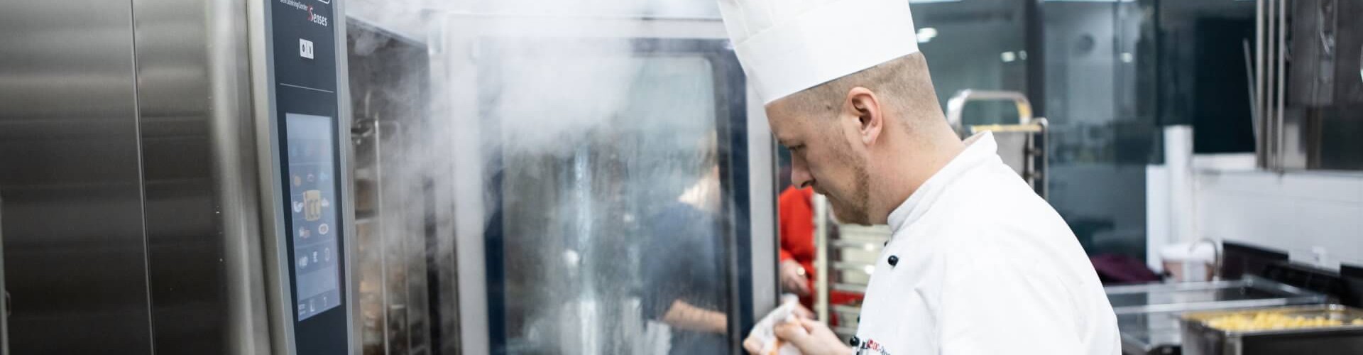 Chef opening steaming RATIONAL SelfCookingCenter combi oven in a professional kitchen.