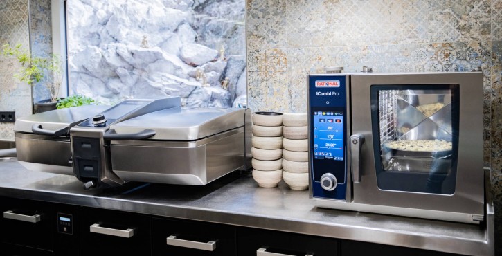 A kitchen with a Rational iCombi Pro oven and a Vario Pro appliance on a stainless steel countertop, with stacked bowls in the background.