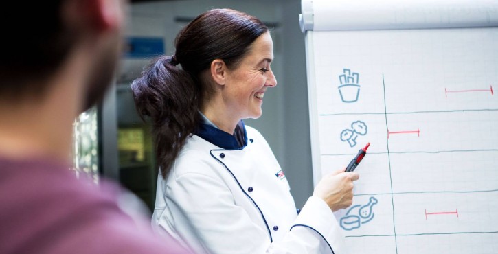Chef expliquant un diagramme de cuisson sur un tableau.