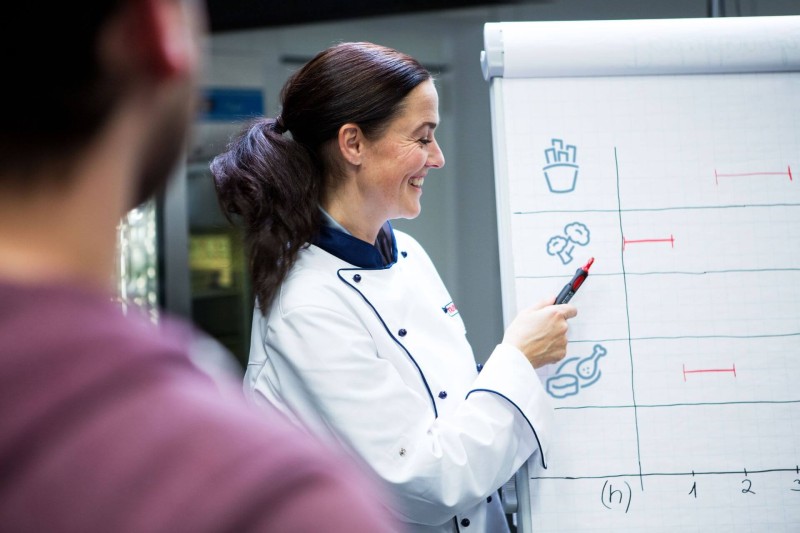 Chef expliquant un diagramme de cuisson sur un tableau.
