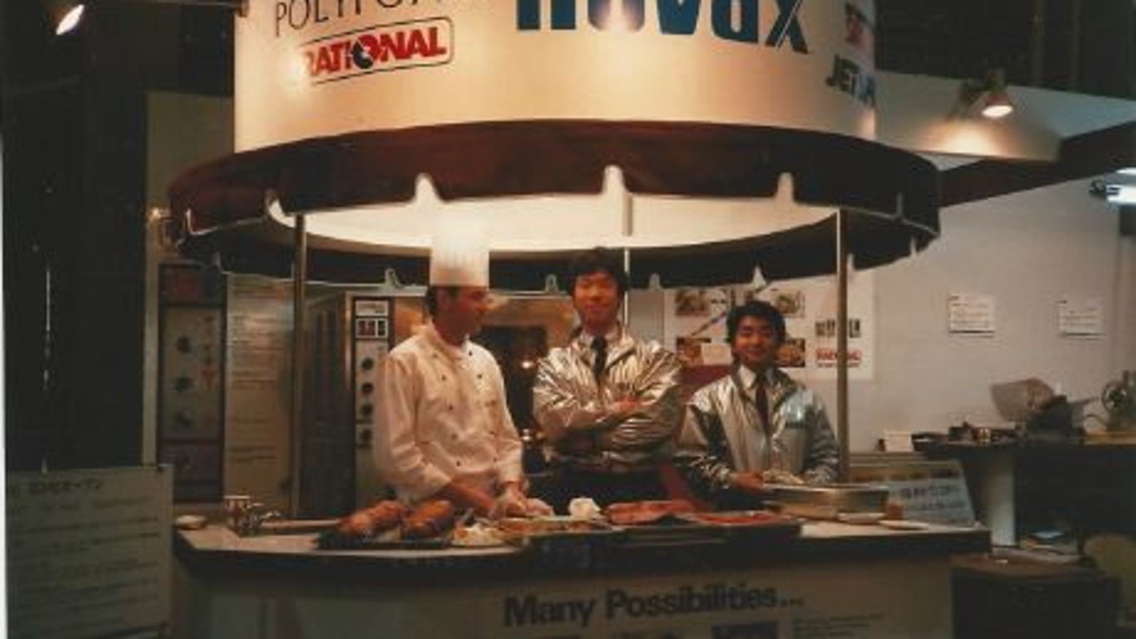A photo of a Rational booth at a trade show in Tokyo featuring chefs cooking at a display with various dishes and a banner.
