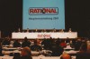 A scene from the 2001 Rational annual meeting featuring a panel of speakers at a long table, with attendees in the audience.
