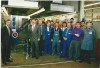 Group photo of employees celebrating the production of the 100,000th Rational combi-steamer in 1996, with a large ribbon displayed.