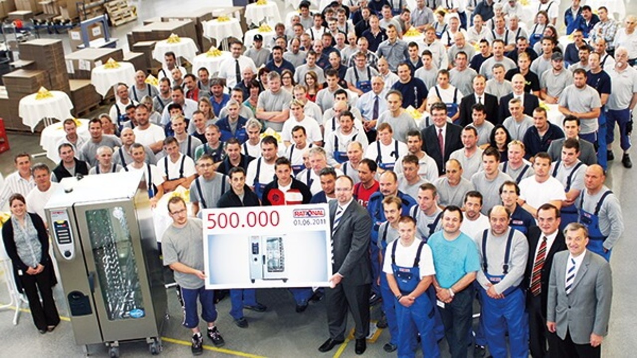 Group photo of Rational employees celebrating the production of the 500,000th combi-steamer on June 1, 2011, holding a sign.