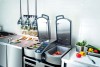 Modern cooking equipment with two open lids, showcasing vegetables and meats, set in a professional kitchen environment.
