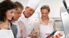Group of four people, including a chef, examining prepared salmon fillets in a kitchen setting, wearing aprons.