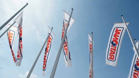 Varias banderas con el logo de Rational ondean al viento bajo un cielo azul.
