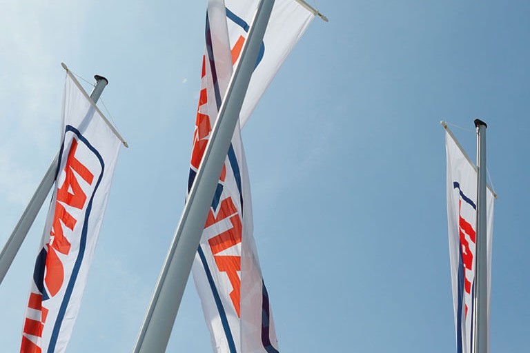 Several flags with the Rational logo are waving in the wind under a blue sky.