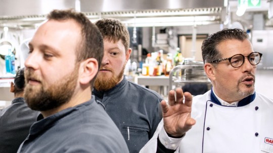 Chefs in a professional kitchen discussing the operation of a Rational device.