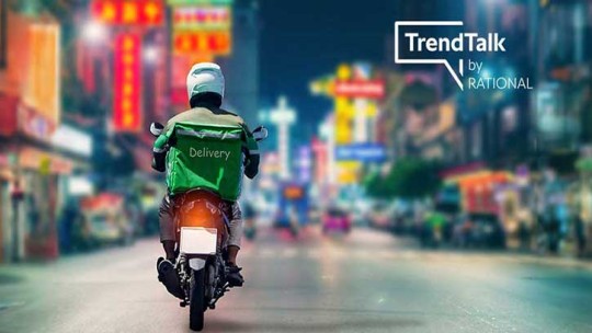 Delivery rider on a motorcycle in a brightly lit city with 