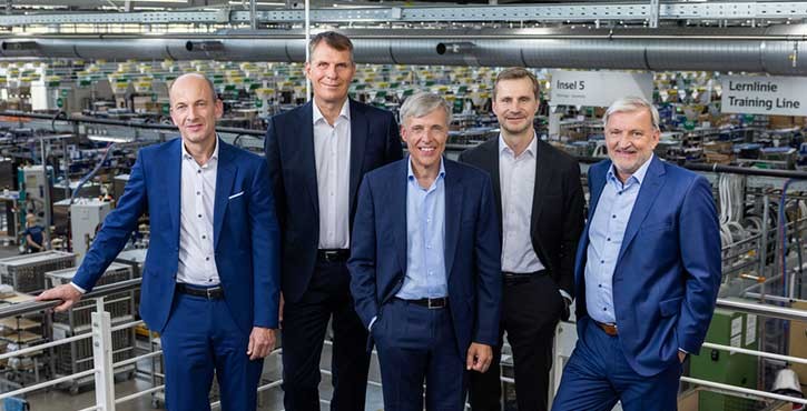 Group portrait of five executives from Rational AG, standing together in a manufacturing facility.
