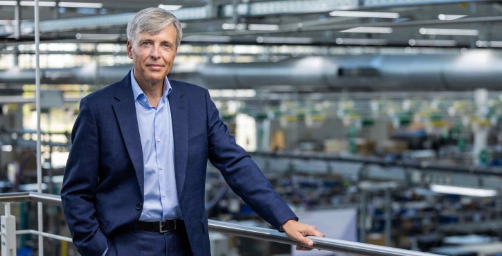 Peter Stadelmann, PDG de RATIONAL AG, debout sur un balcon surplombant une usine moderne.