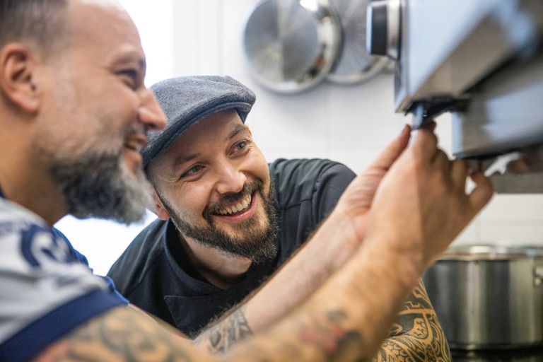 Two men inspect a RATIONAL iCombi Pro together.