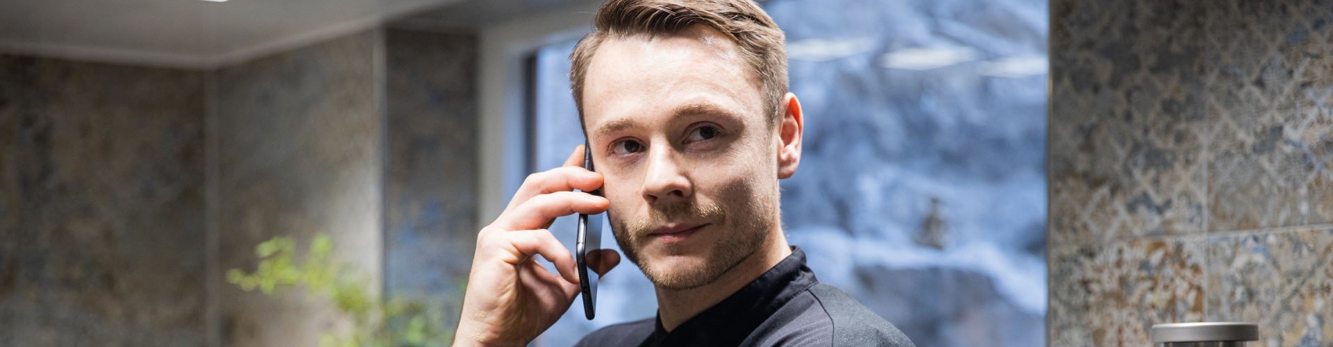 Chef in a black uniform on the phone, iCombi Pro in the background.