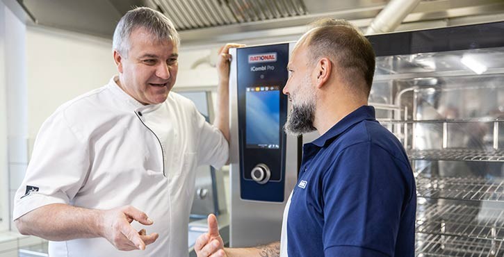 Two men talking in front of a Rational iCombi Pro oven.