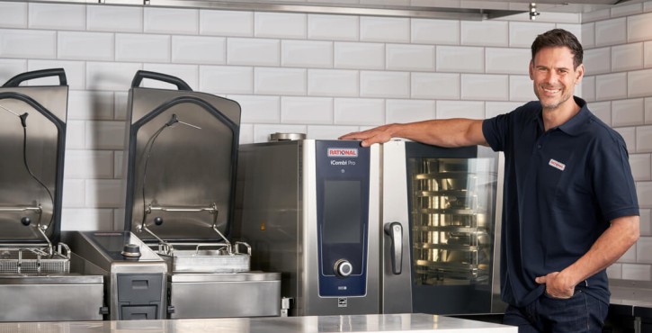 Addetto sorridente accanto al forno professionale RATIONAL iCombi Pro in cucina moderna.