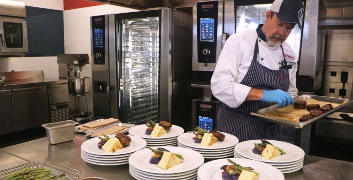 Chef impiatta in una cucina professionale con RATIONAL iCombi Pro forni professionali sullo sfondo.