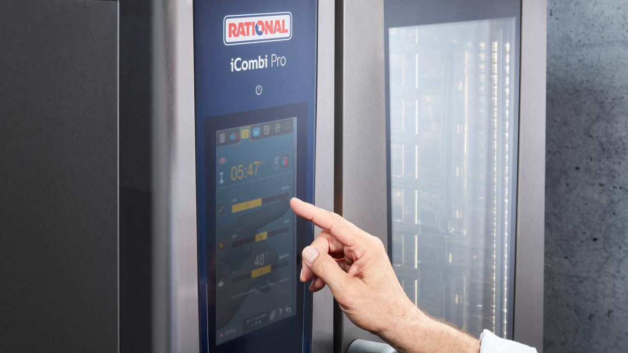 Hand operating touchscreen of RATIONAL iCombi Pro combi-steamer with cooking settings visible.