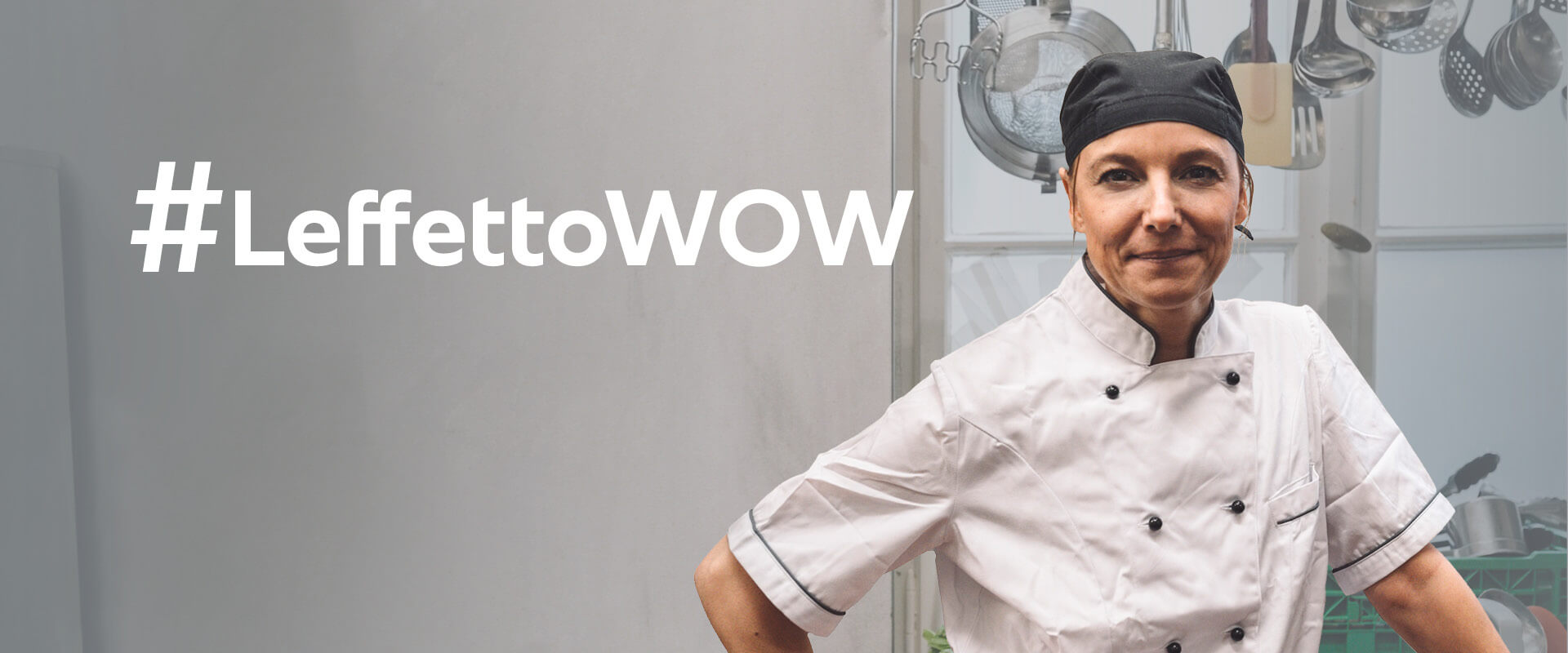 A female chef wearing a white uniform and a black chef hat stands confidently with her arms crossed, beside the text '#TheWOWeffect' in a kitchen filled with cooking utensils.