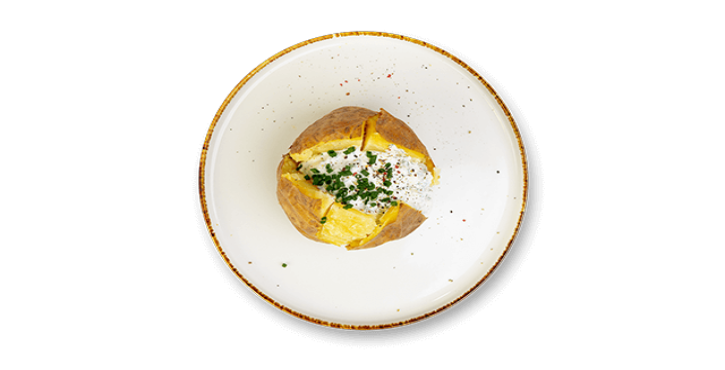 Baked potato with sour cream and chopped herbs on a white plate.