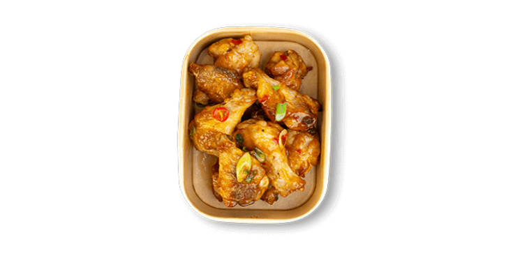 Glazed chicken wings with chili and sesame in a rectangular container.