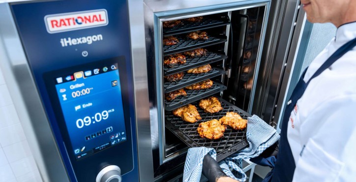Chef taking out a tray of grilled chicken from a RATIONAL iHexagon combi oven.