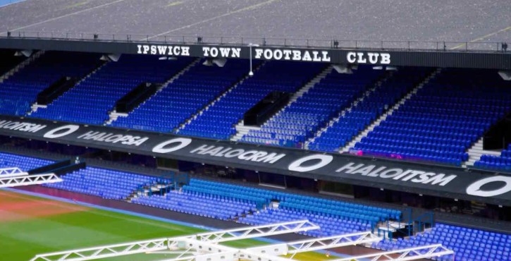 Ipswich Town Football Club stadium with blue seats and advertising banners.