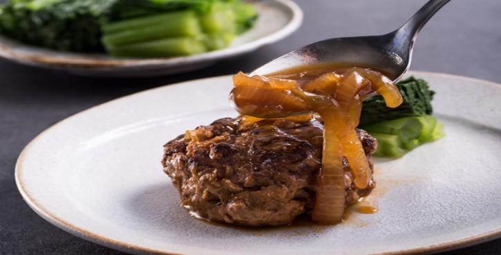 Hamburger sur une assiette, servi avec des accompagnements.