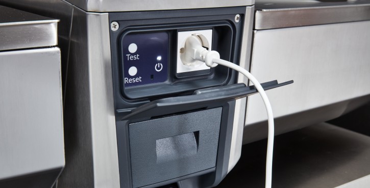 Una vista en primer plano del enchufe de alimentación y el panel de control del dispositivo de cocina iVario Pro 2-S, que presenta botones de prueba y reinicio.