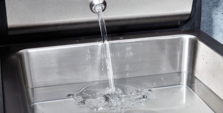 A close-up of the water inlet in a Rational iVario Pro 2-S, showing water flowing into the stainless steel basin.