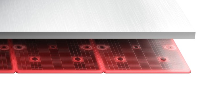 A close-up of a red silicone baking mat with circular holes under a stainless steel surface.