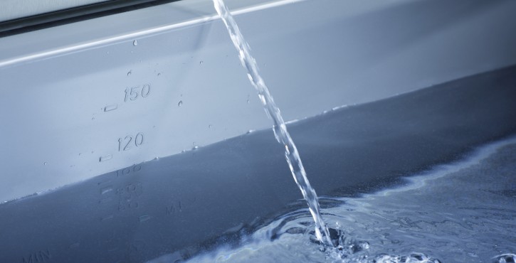 Water flowing into a stainless steel cooking vessel with measurement markings visible on the inside.