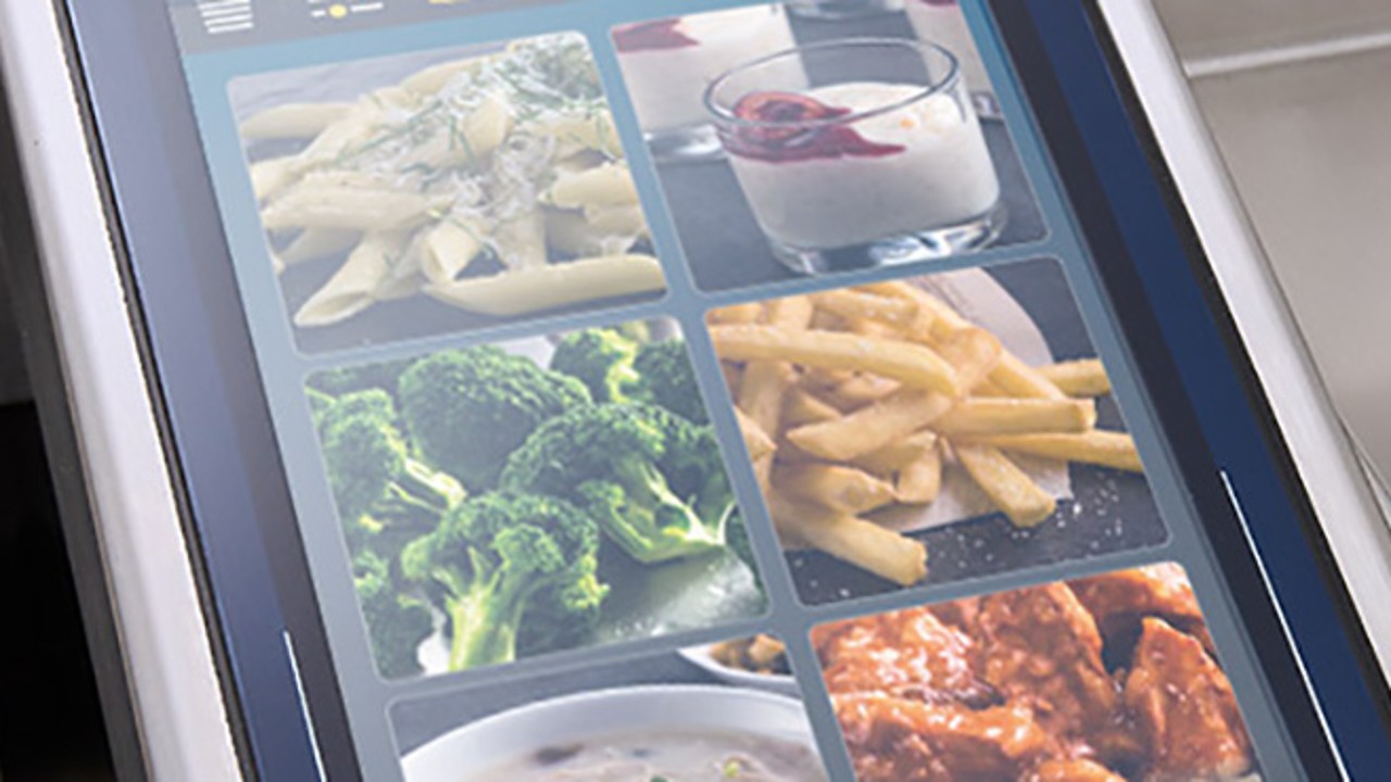 A close-up of the Rational iVario Pro cooking appliance‘s display panel showing various food images, including pasta, broccoli, fries, and dessert.