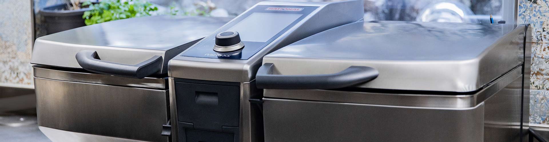 A close-up view of the Rational iVario XS cooking appliance, showcasing its sleek design and control panel.