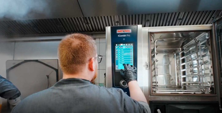 Koch bedient den Touchscreen des offenen RATIONAL iCombi Pro Kombidämpfer in der Küche.