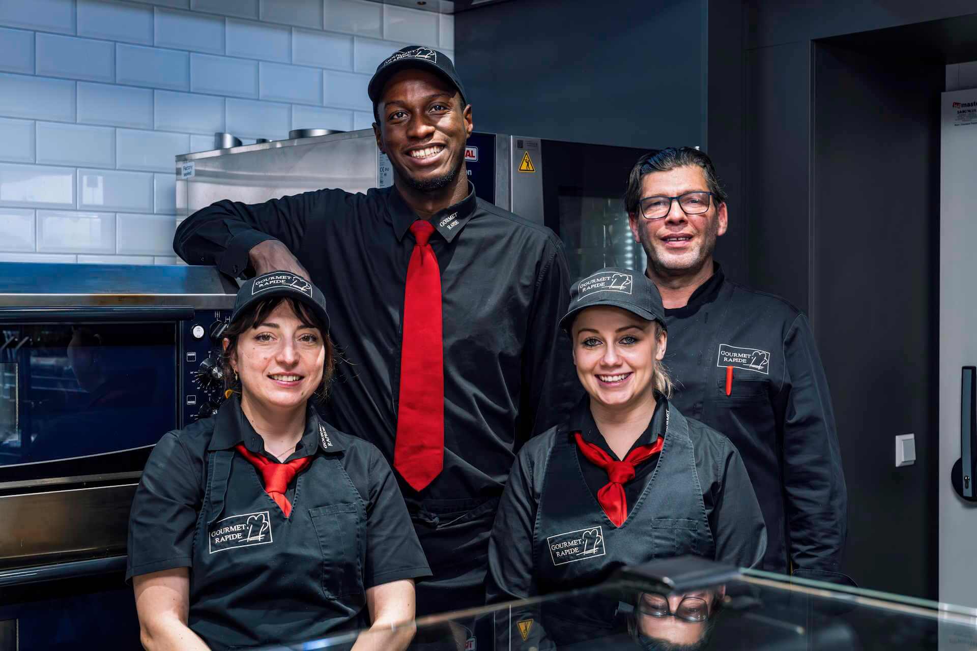 Lächelndes Gourmet Rapide Team posiert in einer Verkaufsküche.