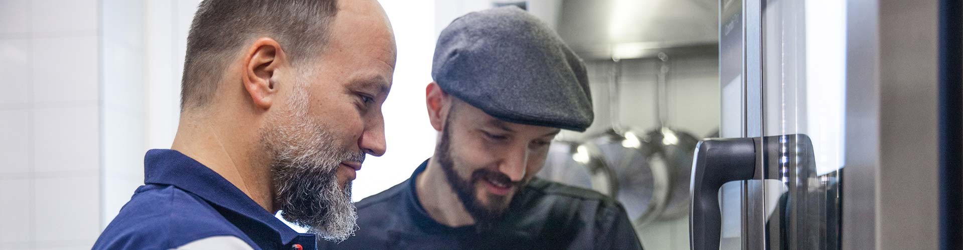 Deux techniciens vérifient un four professionnel dans une cuisine pro.