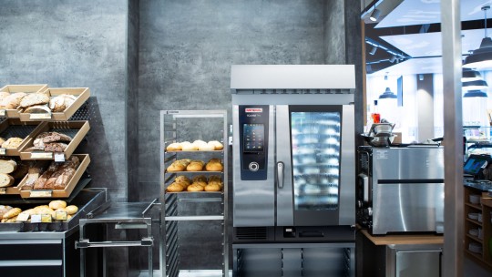 A bakery section with bread shelves and a Rational iCombi Pro oven next to it.