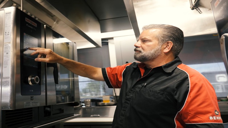 A chef adjusts the settings on a Rational iCombi Pro oven in the kitchen.