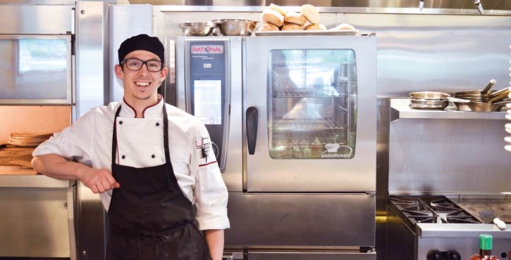 Chef souriant dans une cuisine professionnelle devant un iCombi de Rational.