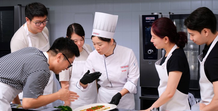 厨师团队在厨房示范菜品摆盘，背景可见RATIONAL iCombi Pro 混合蒸锅。