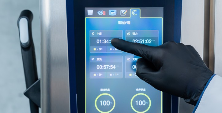 戴手套的工作人员操作RATIONAL 膳酷 混合蒸锅触控屏，选择清洁护理程序。
