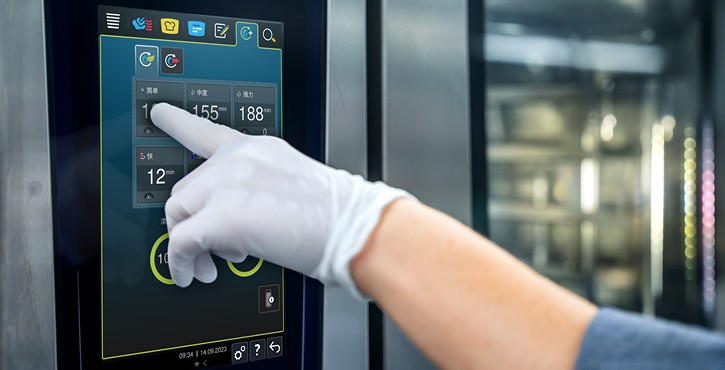 戴手套的工作人员在RATIONAL iCombi Pro 混合蒸锅触控屏上调整清洁时长。